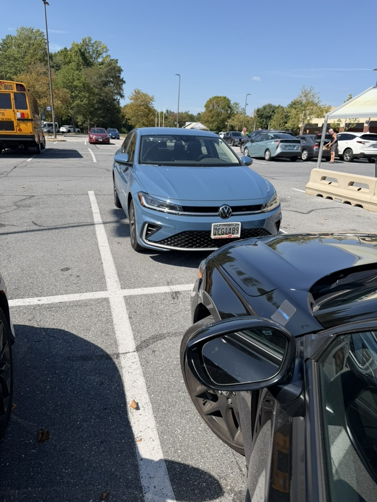 A blue Volkswagen seen from the front in a parking lot